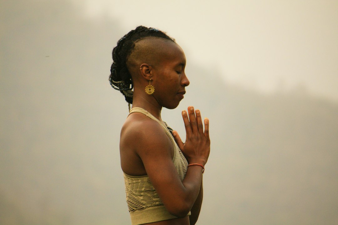 Woman standing side-on, eyes-closed, with her hands together in front of her heart